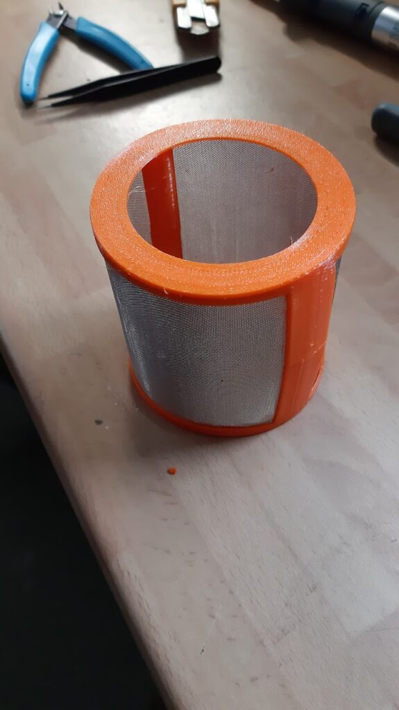 dishwasher filter enclosure, orange tpu, filter mesh inserted, cylindric shape