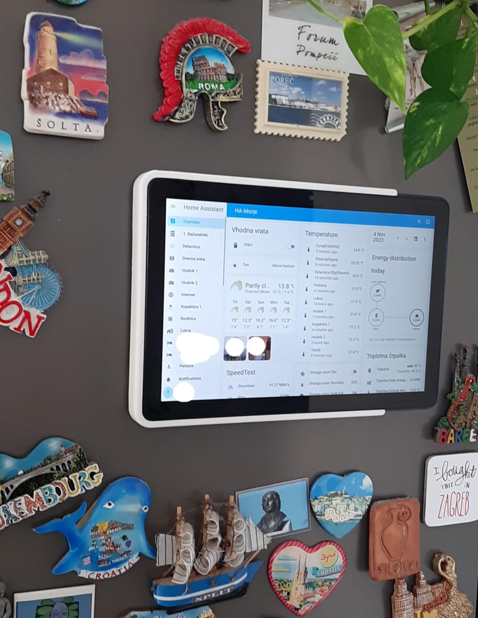 Fire HD tablet on the fridge surrounded by some magnets of places